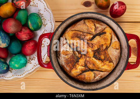 Traditionelle Artisan Brot in Backform und Ostern bemalte Eier, Ansicht von oben. Stockfoto