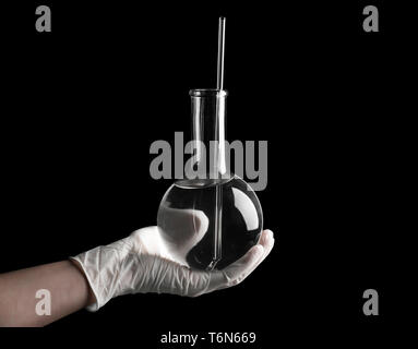 Wissenschaftler Messkolben mit Flüssigkeit auf schwarzem Hintergrund Stockfoto