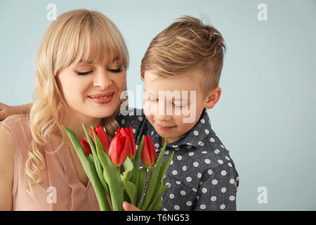 Portrait von niedlichen kleinen Jungen und seiner Mutter mit tulip Blumenstrauß auf grauem Hintergrund Stockfoto