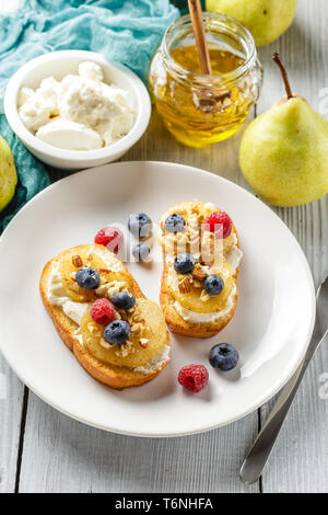 Toast mit Birne, Frischkäse, Nüssen und Honig. Stockfoto