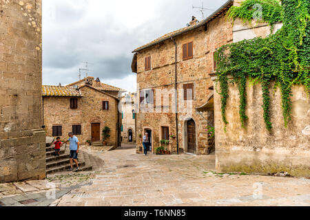 Monticchiello, Italien - 26 August, 2018: Landschaft in der Toskana mit Street in kleinen Stadt Dorf und die Menschen durch die Kirche in typischen Steinhaus außen Stockfoto