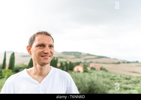 Val D'Orcia Landschaft Dorf in der Toskana, Italien, mit grünen Hügeln mit Bauernhof Landschaft, idyllische malerische Wiese, Felder und glückliche junge Mann Stockfoto