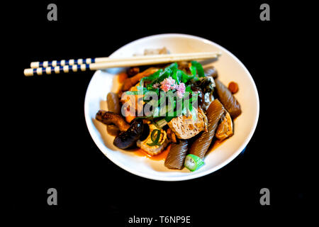 Traditionelle japanische Platte in Restaurant mit Schwarz lackiertem Holz Tisch studio Hintergrund- und Gemüsegericht mit konnyaku, Tofu, grüne negi Zwiebeln ein Stockfoto