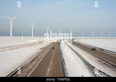 Niederländische Autobahn im Winter mit Windkraftanlagen dahinter Stockfoto