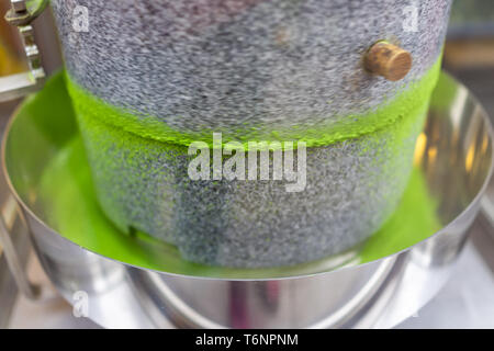 Matcha Grüntee Schleifstein Maschine in Bewegung mit leuchtenden bunten Pulver closeup in Fabrik oder Tee Shop Stockfoto