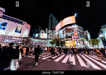 Shibuya, Japan - April 1, 2019: berühmte Kreuzung Zebrastreifen in der Innenstadt von Stadt mit neon rosa leuchtet und die Menschen die kommerzielle Werbung in der Nacht Stockfoto