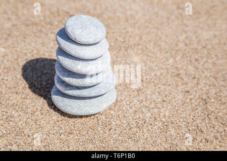 Stapel von grauen Kiesel Steine auf Balance auf einen Sandstrand mit Platz kopieren Stockfoto