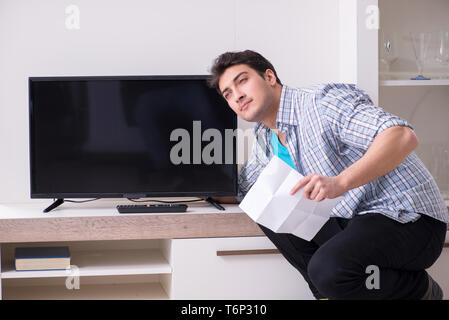 Mann, der versucht, defekte Fernseher zu reparieren Stockfoto