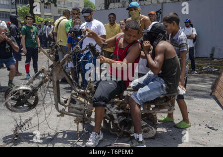 Caracas, Miranda, Venezuela. Mai, 2019. Junge Menschen, die auf der Straße leben (obdachlos) spielen mit einer gebrannten Motorrad, Reste der Zwischenfälle, die sich am 30. April aufgetreten. Tausende von Venezolanern gingen bis März gegen Maduro Regierung zum Tag der Arbeit in Caracas und anderen Städten in Venezuela Protest und (Credit Bild: © Jimmy VillaltaZUMA Draht) Stockfoto