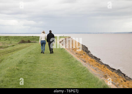 Goldcliff, Newport, Großbritannien. Zum 2. Mai, 2019. Leute Spaziergang am Meer entlang der Wand trotz einem windigen, Grauen und tristen Tag im Goldcliff, Newport, Wales. Das Meer an der Wand mit Blick auf den Fluss Severn mit herrlichem Blick über das Wasser. Credit: Keith Larby/Alamy leben Nachrichten Stockfoto