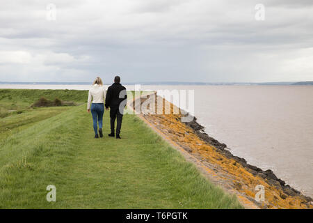 Goldcliff, Newport, Großbritannien. Zum 2. Mai, 2019. Leute Spaziergang am Meer entlang der Wand trotz einem windigen, Grauen und tristen Tag im Goldcliff, Newport, Wales. Das Meer an der Wand mit Blick auf den Fluss Severn mit herrlichem Blick über das Wasser. Credit: Keith Larby/Alamy leben Nachrichten Stockfoto