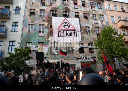 01. Mai 2019, Berlin: Die Teilnehmer des "revolutionären Mayday Demonstration "Spaziergang durch Friedrichshain Vergangenheit ein Haus, auf dem ein Banner mit einer Anarchie Symbol hängt. Foto: Ralf Hirschberger/dpa Stockfoto
