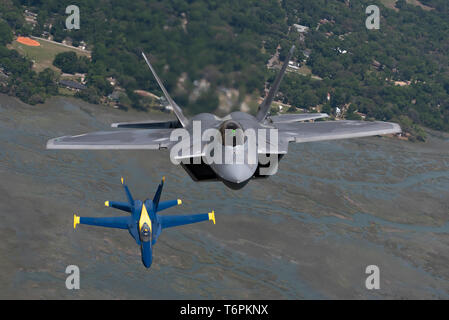 Us Air Force Maj. Paul "Loco" Lopez, F-22 Demo Team Commander/Pilot, fliegt mit der US Navy Blue Angels in Steckplatz formation über den Himmel von Beaufort, South Carolina, 25. April 2019. Diesem historischen Flug empfohlene Zwei von Premier Antenne demonstration Teams der Welt - zum ersten Mal in der Geschichte. (U.S. Air Force Foto von 2 Leutnant Samuel Eckholm) Stockfoto