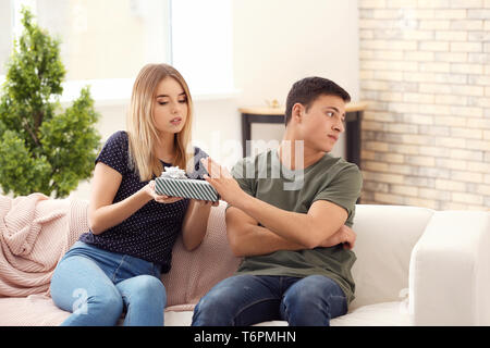 Junger Mann weigert Geschenk von seiner Freundin zu Hause beleidigt Stockfoto