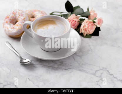 Kaffee mit bunten Donut in weißem Marmor Hintergrund. Stockfoto