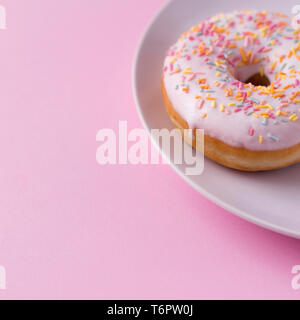 Köstliche Krapfen mit Streuseln auf der Platte an der rosa Tabelle. Stockfoto