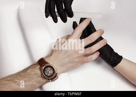 Der Mann für Verfahren in Maniküre Salon. Wellness, manicuring, Verarbeitung der Nägel Nagelfeile. Schönen männlichen Händen. Stockfoto