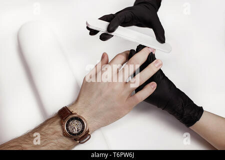 Der Mann für Verfahren in Maniküre Salon. Wellness, manicuring, Verarbeitung der Nägel Nagelfeile. Schönen männlichen Händen. Stockfoto