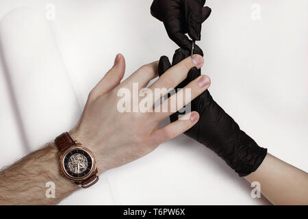 Der Mann für Verfahren in Maniküre Salon. Wellness, manicuring, Entfernen der Nagelhaut Schere. Schönen männlichen Händen. Stockfoto