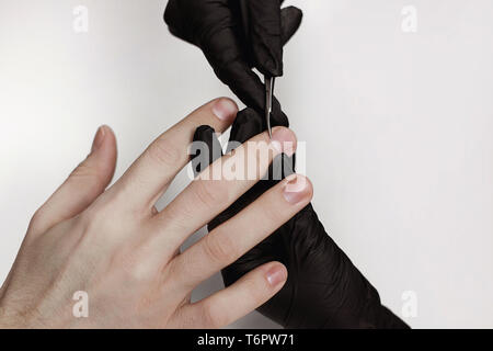 Der Mann für Verfahren in Maniküre Salon. Wellness, manicuring, Entfernen der Nagelhaut Schere. Schönen männlichen Händen. Stockfoto