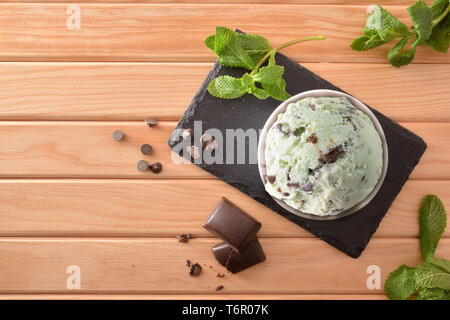 Minze und Schokolade Eisbecher mit Minze und Schokolade Chips auf schiefer Teller auf einen hölzernen Tisch eingerichtet. Horizontale Komposition. Ansicht von oben. Stockfoto