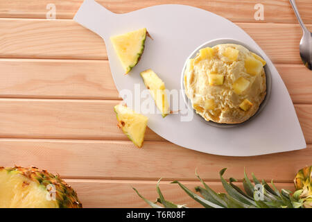 Ananas Eisbecher mit Ananas Stücke und Segmente auf einem hölzernen Tisch eingerichtet. Horizontale Komposition. Ansicht von oben. Stockfoto