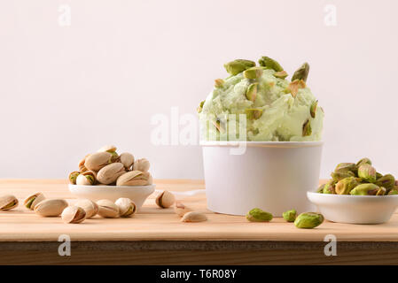 Pistazien Eis Schale mit Pistazien Klumpen auf einem Schild an einem hölzernen Tisch eingerichtet. Horizontale Komposition. Vorderansicht. Stockfoto