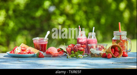 Frische, gesunde, lebendige Sommer Berry Smoothie Schüsseln und Säfte an einem hellen Tisch im Freien. Stockfoto