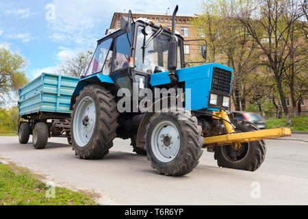 Eine alte kleine blaue Traktor mit Anhänger steht am Rande einer Stadt Straße Straße Stockfoto