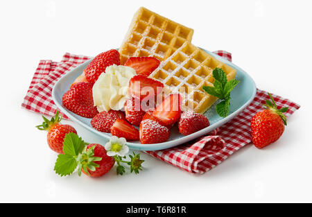 Frische reife Erdbeeren mit Waffeln und Creme auf einem rustikalen karierte rote und weisse Serviette über einem weißen Hintergrund serviert. Stockfoto