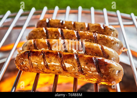 Lecker und heiß gegrillte Würstchen in Nahaufnahme auf Gitter Grill im Freien Stockfoto