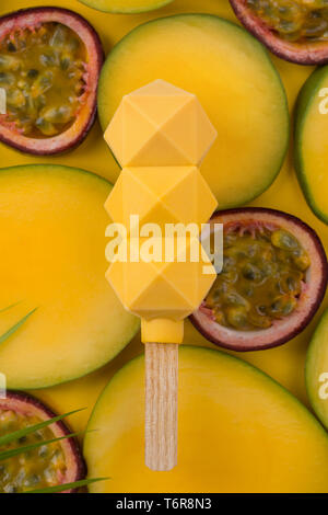 Eis in Scheiben geschnittenen tropischen Früchten Hintergrund. Popsicle. molekulare Küche. Eis auf einem Stock, auf Mango und pashion Obst Hintergrund. Eis mad Stockfoto