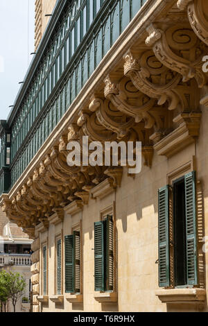 Eine Reihe von dekorierten Kalksteinkorbellen stützt den Balkon der Grandmaster's galleria an der Ecke Old Theatre St des Grandmaster's Palace in Valletta Stockfoto