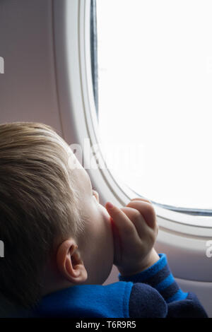 Little Boy auf der Suche durch die Ebene Fenster Stockfoto