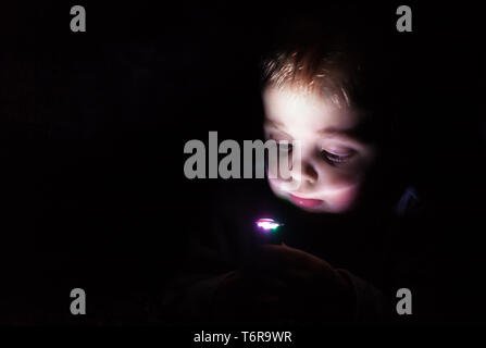 Junge spielt mit der Taschenlampe im Dunkeln Stockfoto