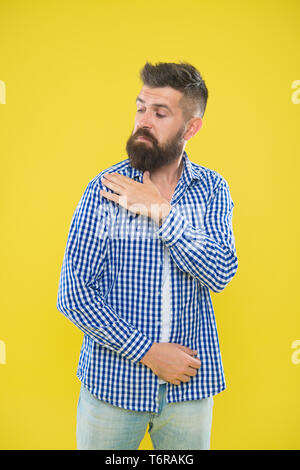 Shake It Off. Sommer Hipster. Brutale bärtigen Hipster in kariertem Hemd Bürste Staub von der Schulter. Männliche Mode. Pedantische Mann mit Bart auf gelben Hintergrund. Reifer Mann. Alles muss perfekt sein. Stockfoto