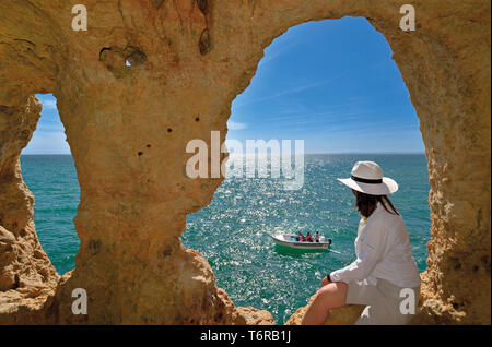 Frau auf der Suche von natürlichen Höhle Fenster zu Green Ocean und touristischen Boot an einem sonnigen Tag Stockfoto