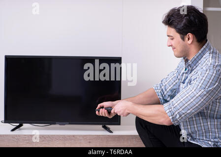 Mann, der versucht, defekte Fernseher zu reparieren Stockfoto