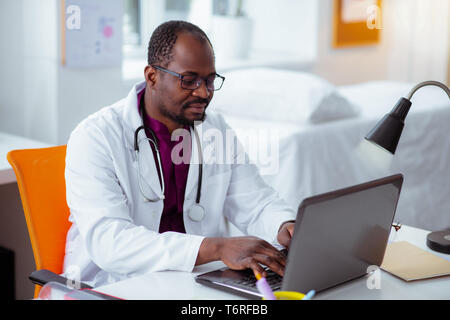Dunkle Bärtigen dunkelhäutige medizinischer Wissenschaftler arbeiten am Laptop Stockfoto