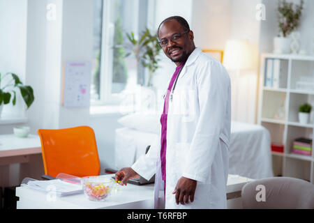 Medizinische Wissenschaftler tragen weiße Jacke in der Nähe von Arbeitstisch Stockfoto