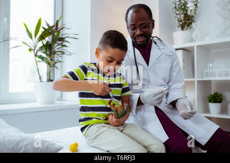 Lustige Patienten der Kinderarzt die Einspritzung für Spielzeug Dragon Stockfoto
