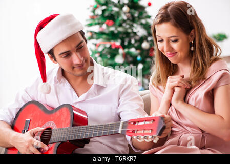 Junges Paar Gitarre spielen zu Weihnachten Stockfoto