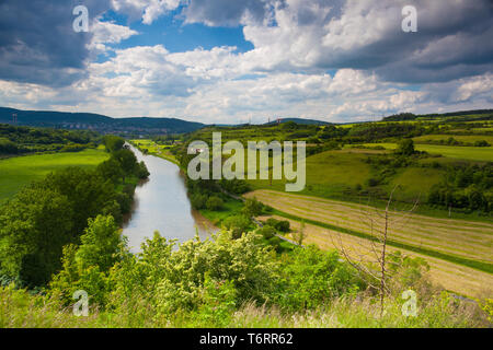 Blick vom Hügel in das Tal mit dem Fluss Berounka. Fluss Berounka, Kalksteinfelsen, Wiesen, Felder und Eisenbahn. Stockfoto