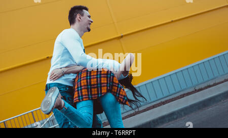 Junge lächelnde Paar in Liebe Mann hält attraktive Frau hand, Zeit miteinander zu verbringen, genießen - auf gelbem Hintergrund Stockfoto