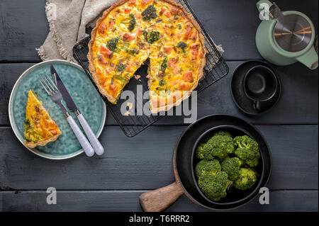 Traditionelle runde Torte mit Brokkoli, Lachs und Käse. Lebensmittel von Gesunden und gesunde Lebensmittel. Pie cut zum Frühstück. Dark Photo. Ansicht von oben Stockfoto