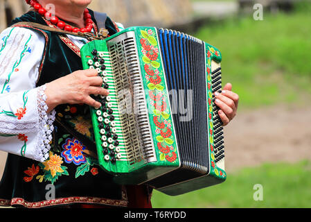 In der Ukraine. Eine ältere Frau in der Ukrainischen Kostüm spielt das Akkordeon an der ethnischen Festival in Petrikovka, Dnepropetrovsk region, Frühling, Sommer. Stockfoto