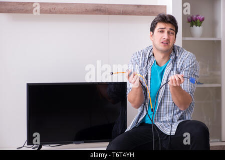 Mann, der versucht, defekte Fernseher zu reparieren Stockfoto