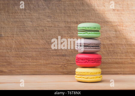 Vier bunte leckere französische Macarons auf Holz Textur isoliert Stockfoto