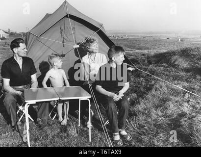 Camping in den 1960er Jahren. Eine Familie außerhalb Ihres Zeltes. Eine einfache und billige Art und Weise Ihren Urlaub zu verbringen. Die wichtigen Klapptisch ist sichtbar, und sie nahm es mit leichter, dass sie weise und nimmt wenig Platz im Kofferraum des Autos. Schweden 1962 Stockfoto