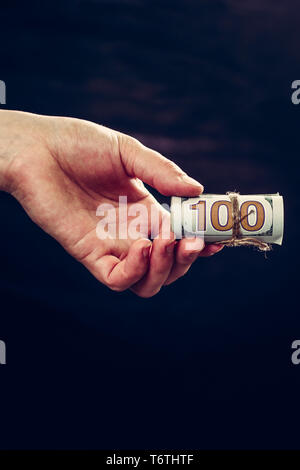 Eine Frau Hand 100 Banknoten, eine Überweisung oder einen dunklen Hintergrund. 2019 Stockfoto